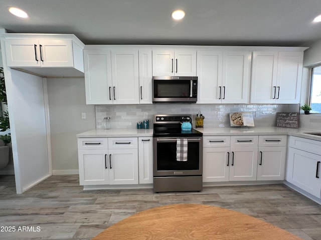 kitchen featuring white cabinets, appliances with stainless steel finishes, tasteful backsplash, and light hardwood / wood-style floors