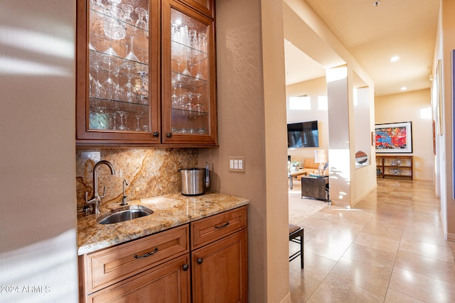 bar with sink, decorative backsplash, fridge, light tile patterned floors, and light stone countertops