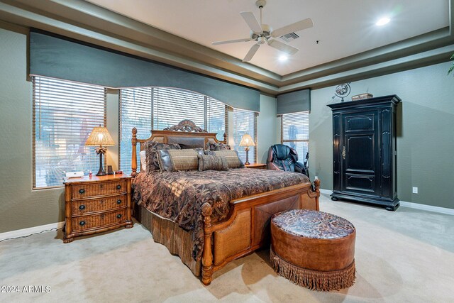 carpeted bedroom with ceiling fan and a raised ceiling