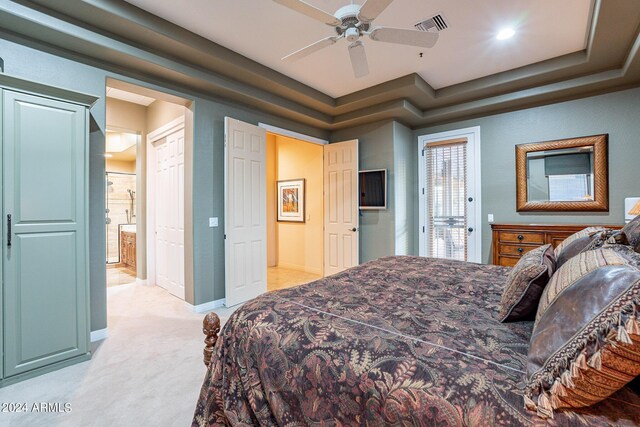 carpeted bedroom with ceiling fan, a raised ceiling, and connected bathroom