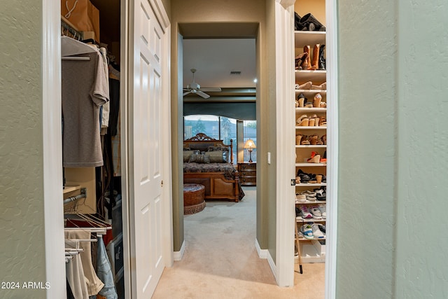 spacious closet with ceiling fan and light colored carpet