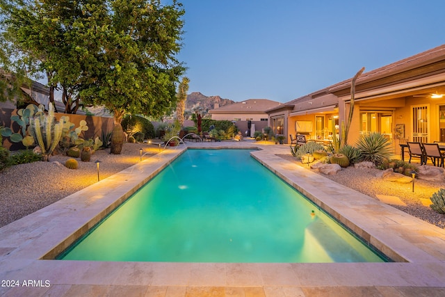 pool at dusk featuring a patio area and pool water feature