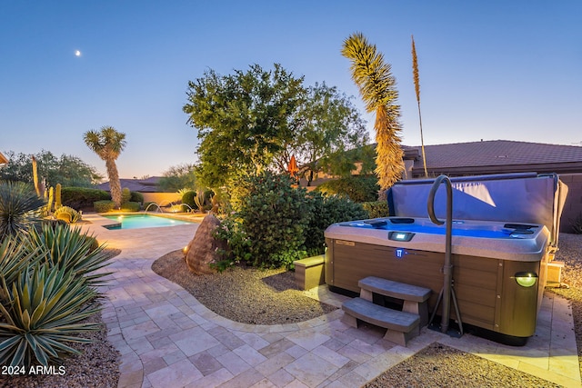 patio terrace at dusk with a swimming pool with hot tub