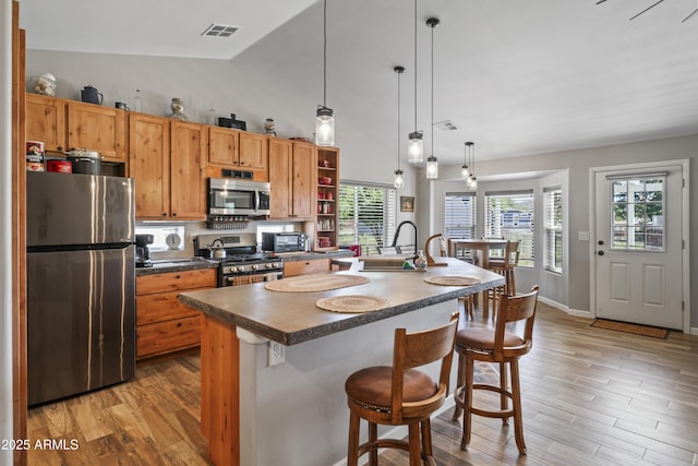17696 W Foothill Rd, Yarnell, AZ 85362 - kitchen with appliances with stainless steel finishes, dark countertops, light wood-style floors, an island with sink, and high vaulted ceiling