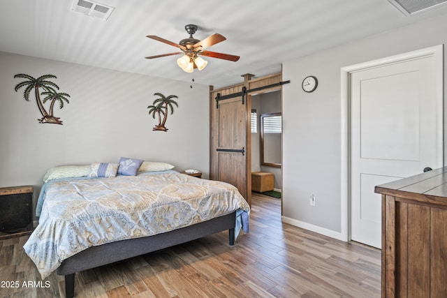 17696 W Foothill Rd, Yarnell, AZ 85362 - bedroom with a barn door, wood finished floors, and ceiling fan