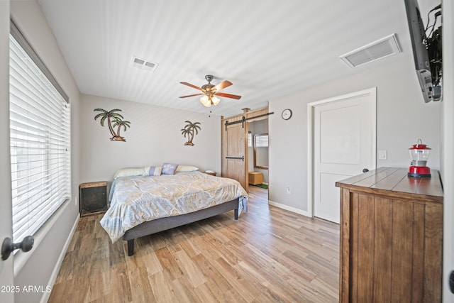 17696 W Foothill Rd, Yarnell, AZ 85362 - bedroom featuring a barn door, multiple windows, light wood finished floors, and a ceiling fan