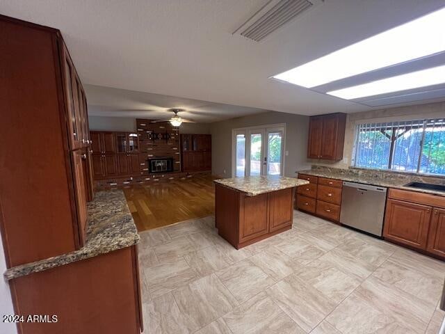 kitchen with french doors, a center island, dishwasher, ceiling fan, and light stone countertops