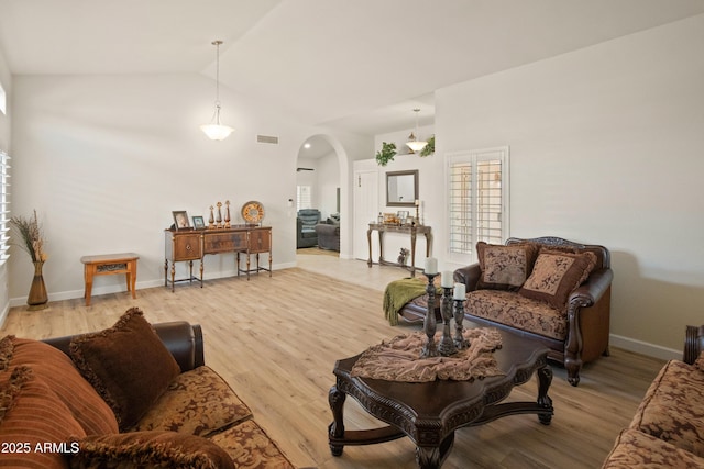 21335 N 64th Ave, Glendale, AZ 85308 - living area featuring baseboards, vaulted ceiling, light wood-style floors, visible vents, and arched walkways