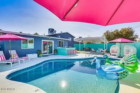 view of swimming pool featuring a bar and a patio