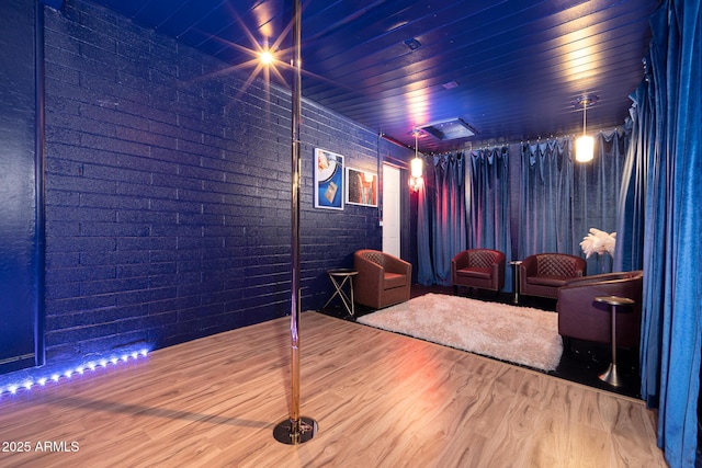 home theater room featuring brick wall and hardwood / wood-style flooring