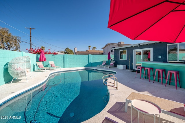 view of pool with an outdoor bar and a patio area