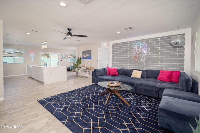 living room with ceiling fan, light hardwood / wood-style flooring, and sink