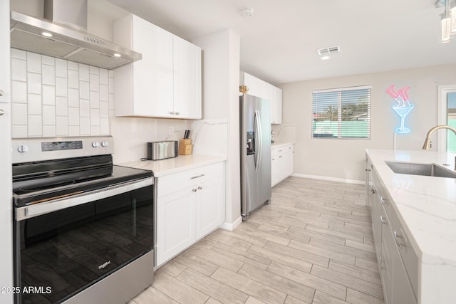 kitchen with stainless steel appliances, wall chimney range hood, white cabinetry, and sink