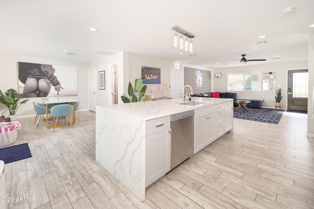 kitchen with stainless steel dishwasher, a kitchen island with sink, white cabinets, ceiling fan, and sink