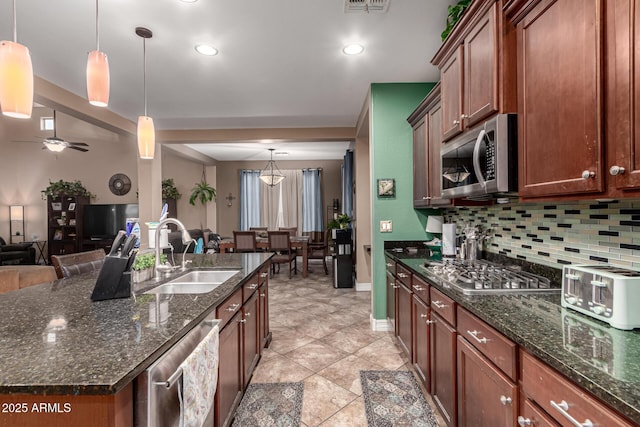 kitchen featuring sink, a kitchen island with sink, appliances with stainless steel finishes, and pendant lighting