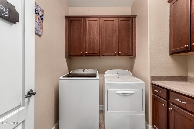 clothes washing area with cabinets and washer and dryer