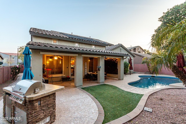 rear view of house with a fenced in pool, a patio, and area for grilling