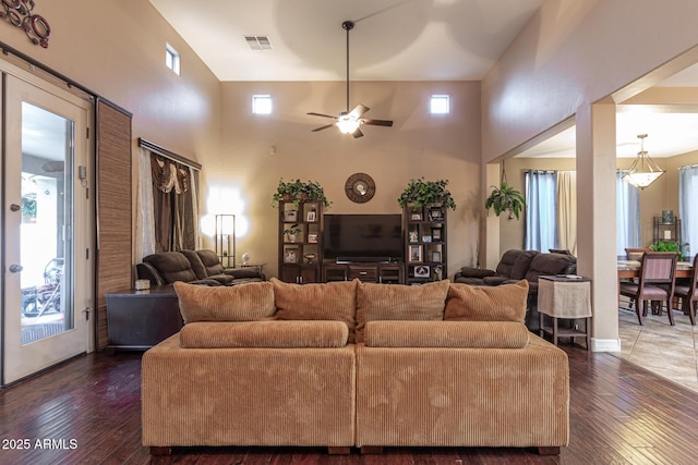 living room with dark wood-type flooring, a towering ceiling, and a wealth of natural light