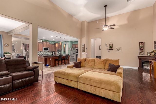 living room with ceiling fan and dark wood-type flooring