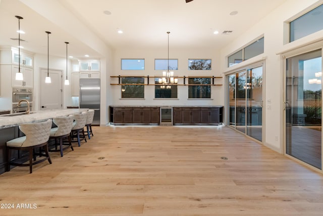 kitchen featuring wine cooler, light stone countertops, light hardwood / wood-style flooring, and stainless steel built in refrigerator