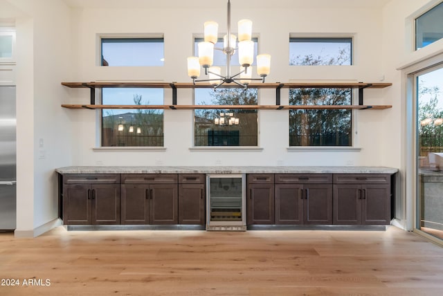 bar featuring pendant lighting, wine cooler, light hardwood / wood-style flooring, a notable chandelier, and dark brown cabinets