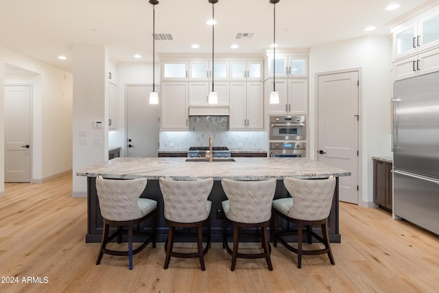 kitchen featuring a kitchen island with sink, white cabinets, and stainless steel appliances