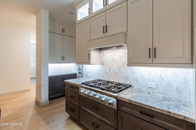 kitchen with light stone countertops, light wood-type flooring, dark brown cabinetry, white cabinetry, and stainless steel gas stovetop