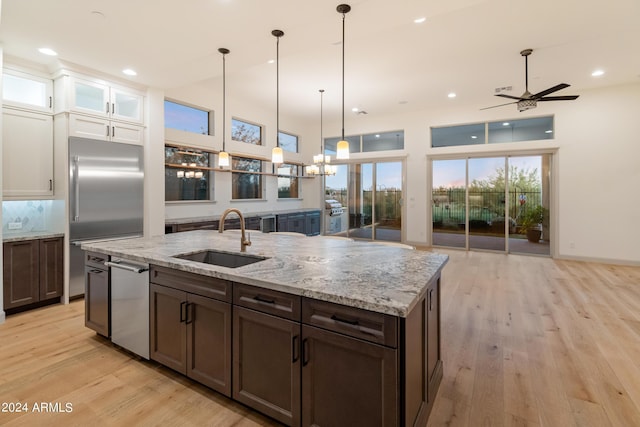 kitchen featuring ceiling fan, sink, stainless steel appliances, decorative light fixtures, and light wood-type flooring