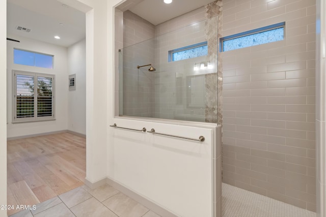 bathroom with tiled shower and hardwood / wood-style flooring