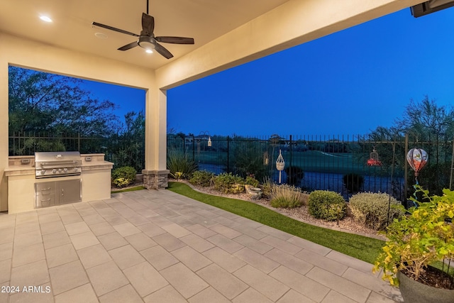 patio terrace at dusk with area for grilling and ceiling fan