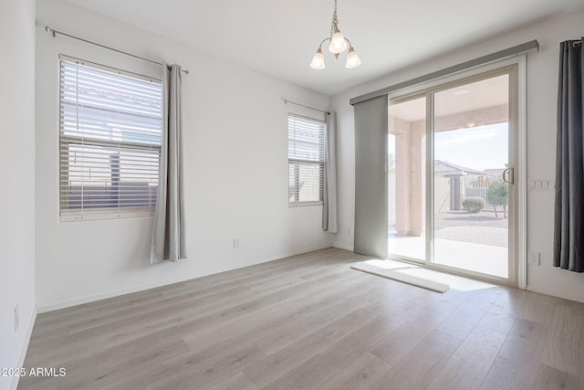 unfurnished room with a notable chandelier and light wood-type flooring