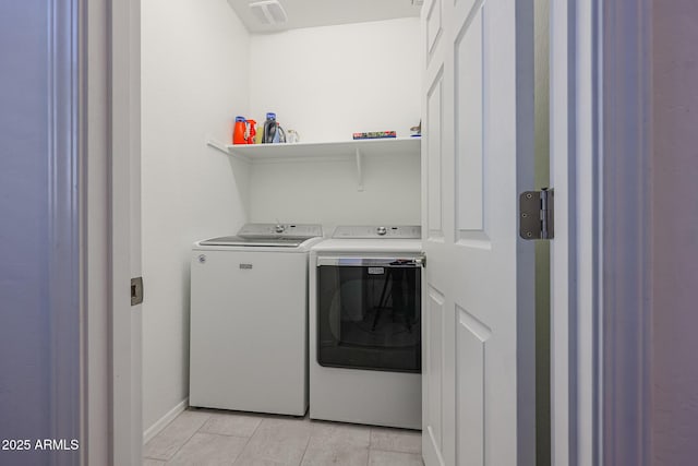 clothes washing area with washer and clothes dryer and light tile patterned floors