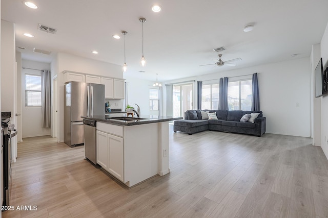 kitchen with appliances with stainless steel finishes, a center island with sink, white cabinetry, and sink