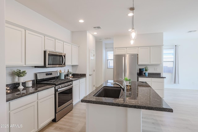 kitchen with white cabinetry, a kitchen island with sink, sink, and appliances with stainless steel finishes