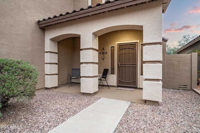 exterior entry at dusk featuring a patio area