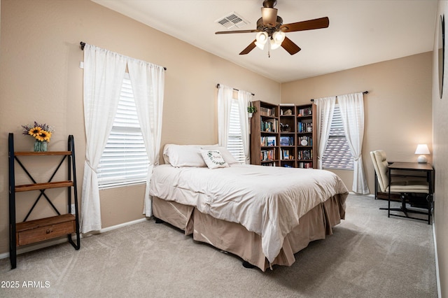 bedroom with ceiling fan, light colored carpet, and multiple windows