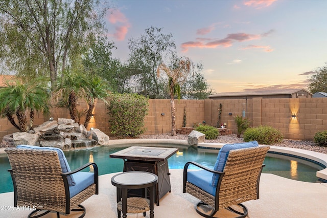 pool at dusk featuring pool water feature