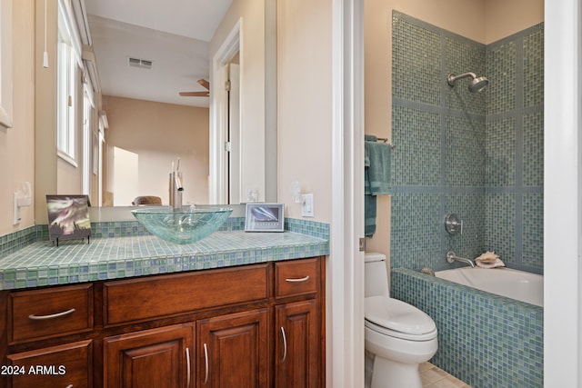 full bathroom with tile patterned floors, vanity, tiled shower / bath combo, and toilet