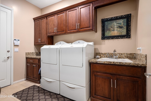 clothes washing area with cabinets, light tile patterned floors, washing machine and dryer, and sink