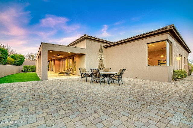 back house at dusk with a patio and ceiling fan