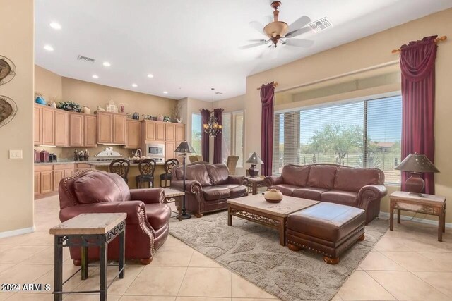 tiled living room with ceiling fan with notable chandelier and sink