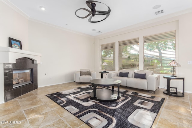 living room featuring plenty of natural light, ceiling fan, crown molding, and a tiled fireplace