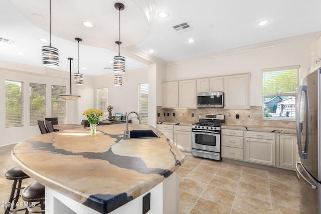 kitchen with a kitchen island with sink, pendant lighting, stainless steel appliances, and sink