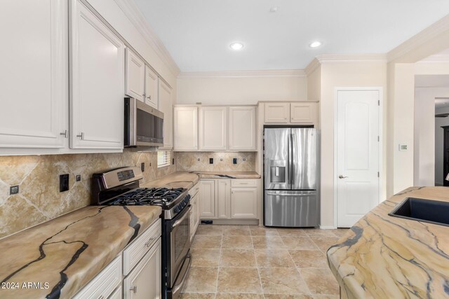 kitchen featuring white cabinets, backsplash, stainless steel appliances, and ornamental molding