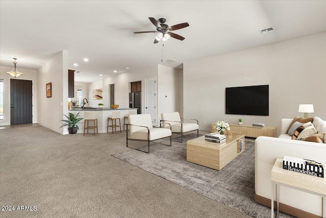 carpeted living room with ceiling fan