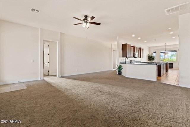 unfurnished living room with light colored carpet, ceiling fan, and sink