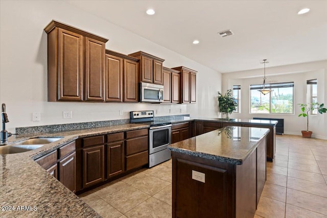 kitchen with hanging light fixtures, sink, light tile patterned floors, and stainless steel appliances