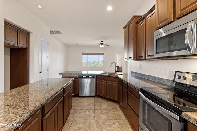 kitchen featuring ceiling fan, sink, stone countertops, light tile patterned floors, and appliances with stainless steel finishes