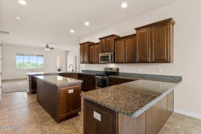 kitchen featuring ceiling fan, sink, stainless steel appliances, kitchen peninsula, and a kitchen island