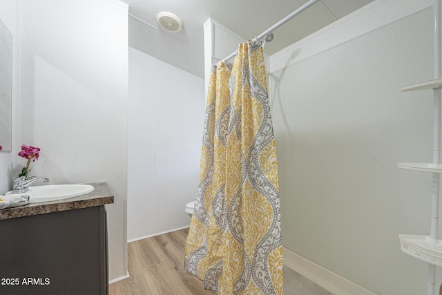 bathroom featuring toilet, hardwood / wood-style flooring, a shower with shower curtain, and vanity